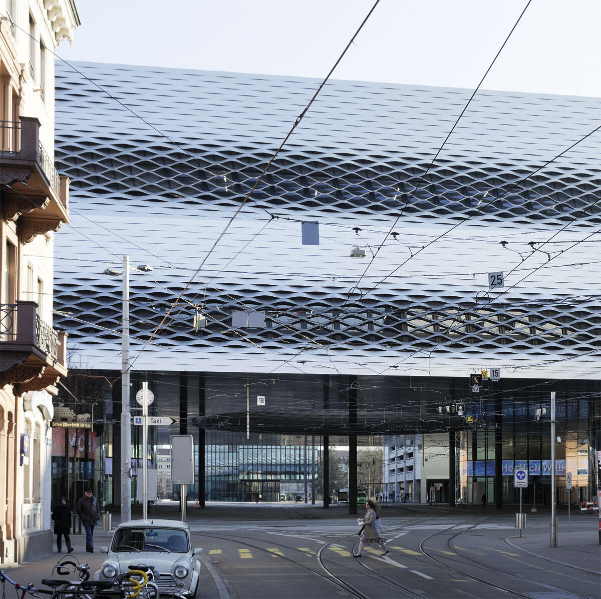 Blick aus der Clarastrasse auf die neuen Hallen von Herzog & de Meuron und den überbauten Messeplatz Basel. Im Hintergrund der Fuss des Messeturms. Die Fassade aus 15 000 Aluminiumbändern öffnet sich an ausgewählten Stellen und stellt den Bezug zum menschlichen Massstab her.