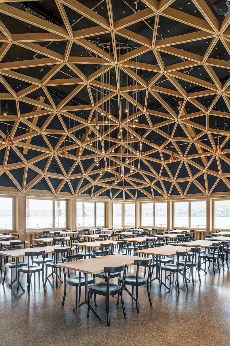 Ein Gewölbe aus Holzstäben, geplant vom «Geometrie Ingenieur» Urs B. Roth, überspannt den Speisesaal, seitlich liegt die Lounge. Bild: Juliet Haller / Amt für Städtebau