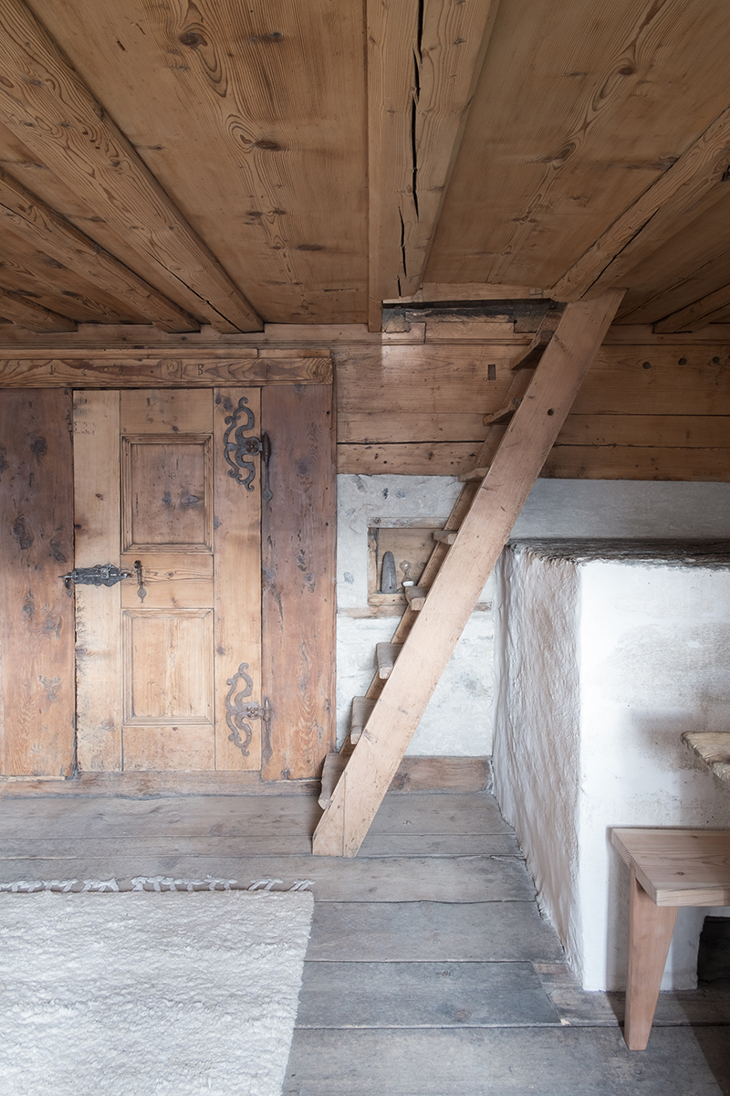 Restaurierter Holzofen sowie originale Stubentüre mit kunstvoll geschmiedeten Beschlägen und Türschloss.